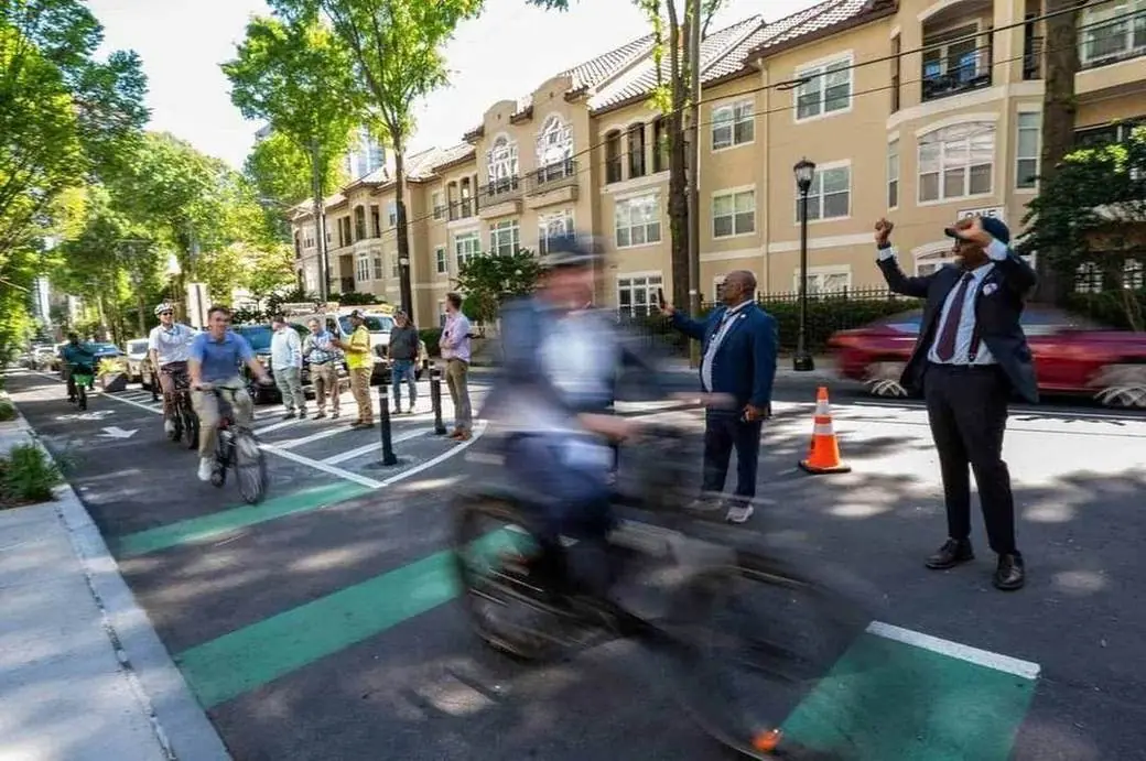 Officials celebrate a cyclist on a new protected bike lane in Midtown Atlanta