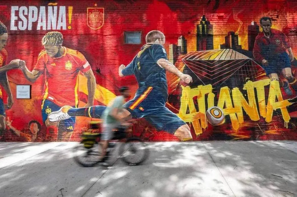 A cyclist rides past the ¡España! mural during Casa España in Atlanta